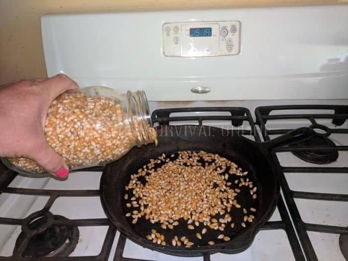pouring corn kernels into pre-heated cast iron skillet