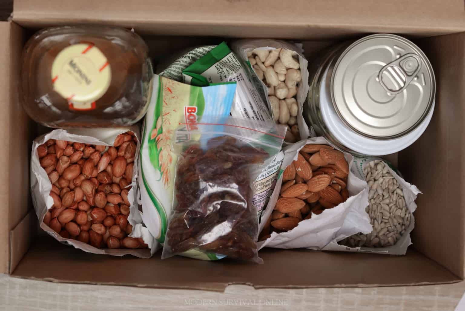 nuts, dried fruit, cans of food, and olive oil in a box