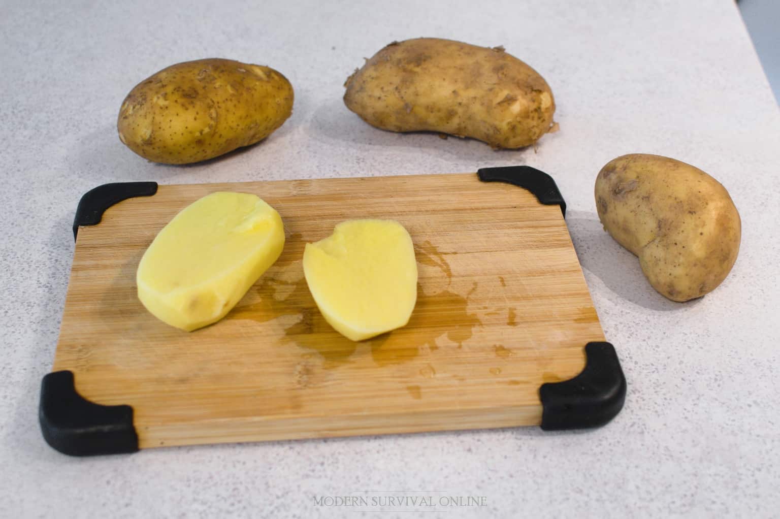 sliced raw potato on cutting board next to other potatoes